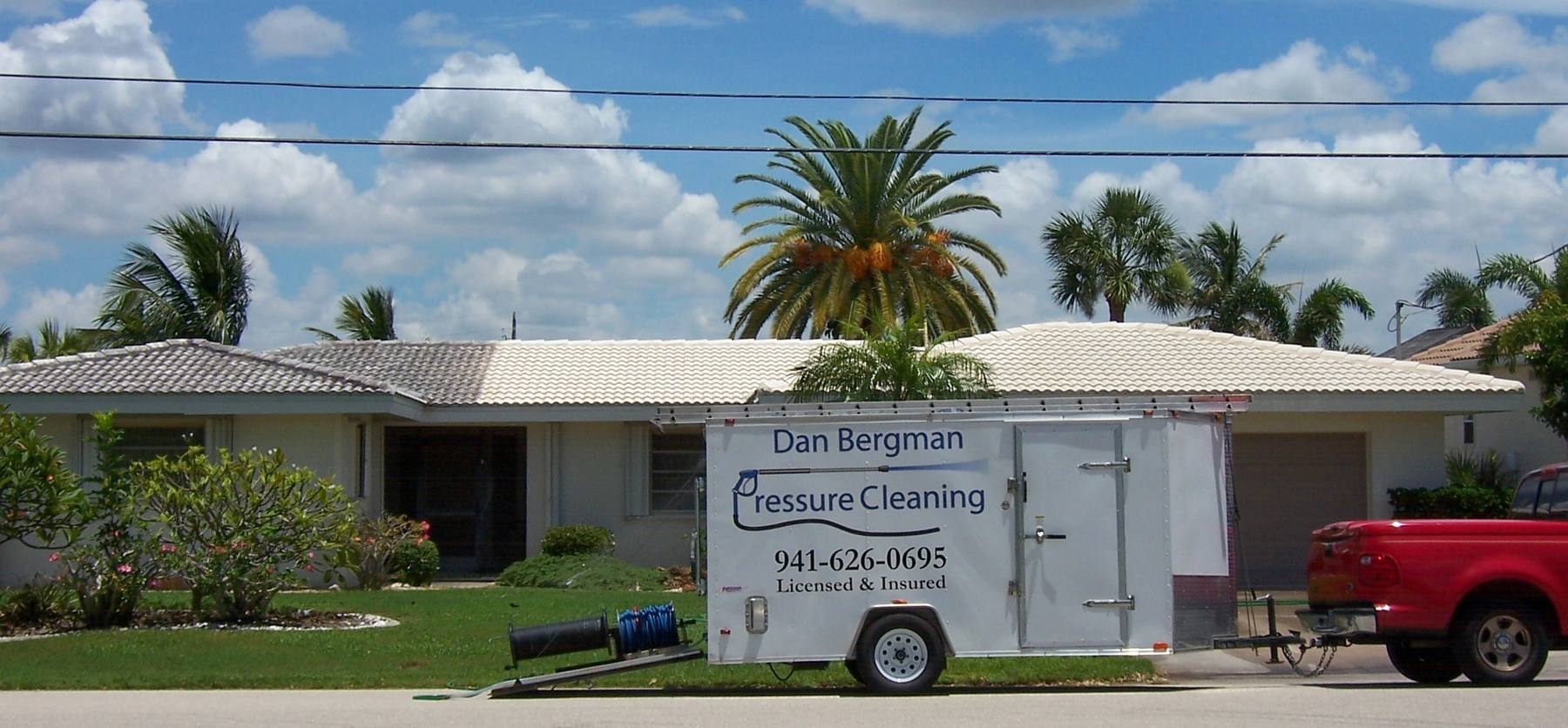 The Dan Bergman Pressure Cleaning trailer and truck outside a Florida home with a freshly cleaned white tile roof